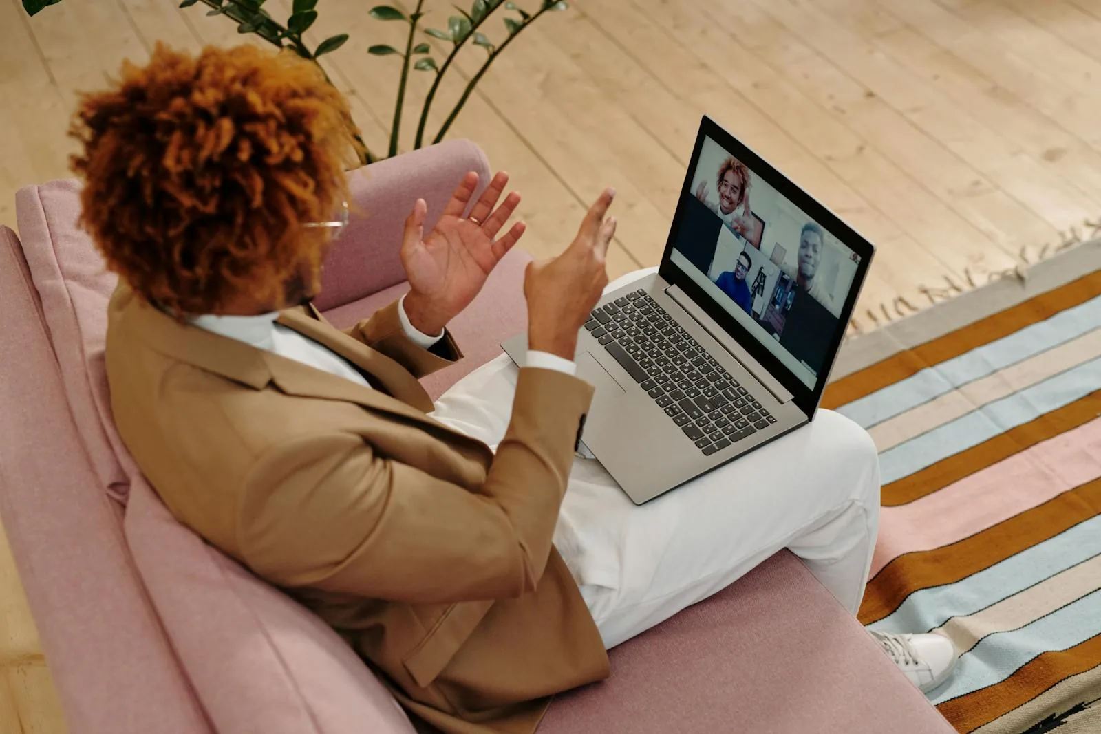 A person attending a video health visit on a laptop from a comfortable home setting